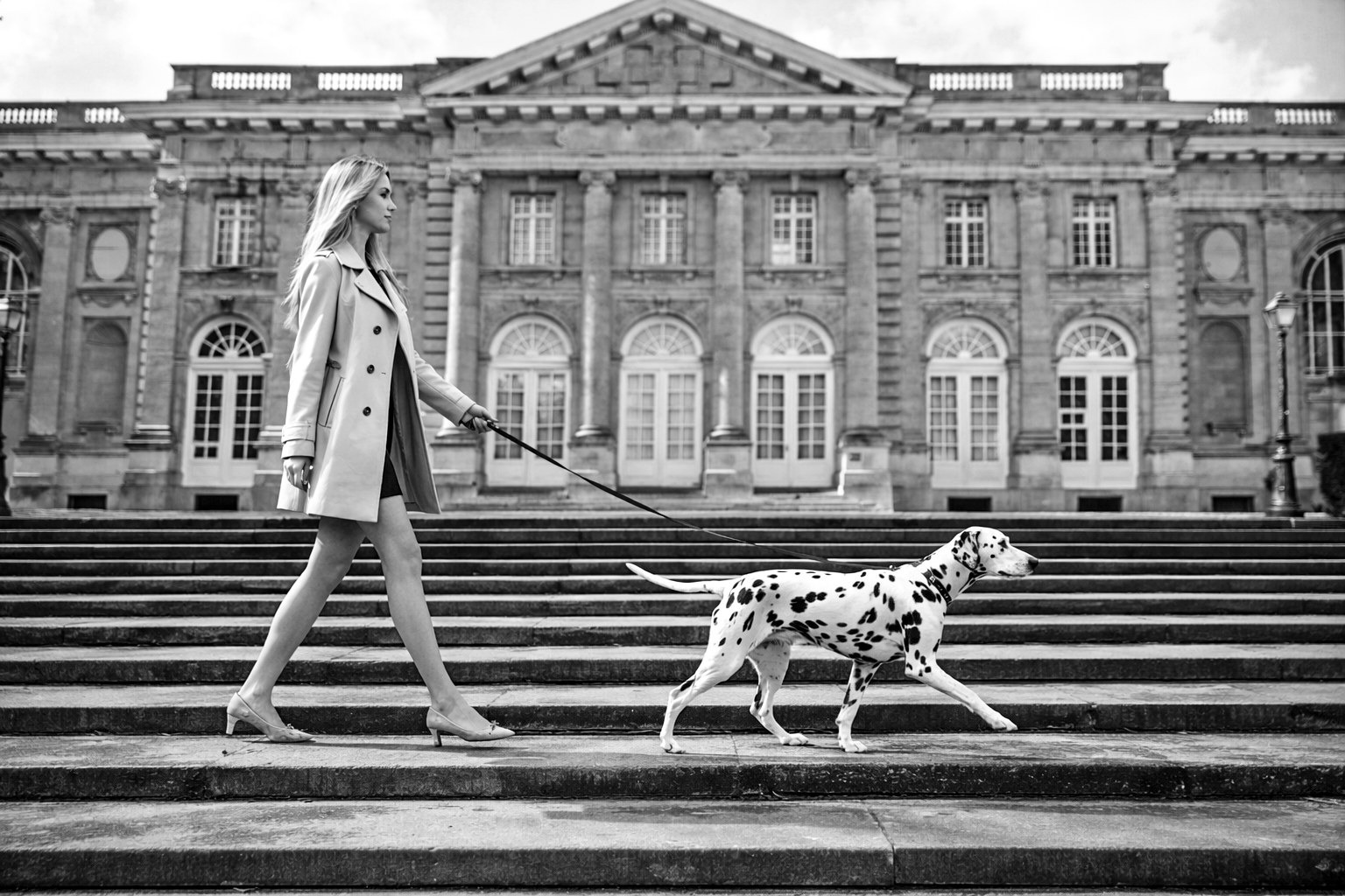 Femme avec un dalmatien devant un bâtiment classique
